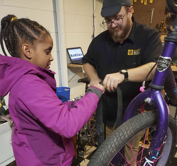 Jacob helping a little girl fix her bicycle